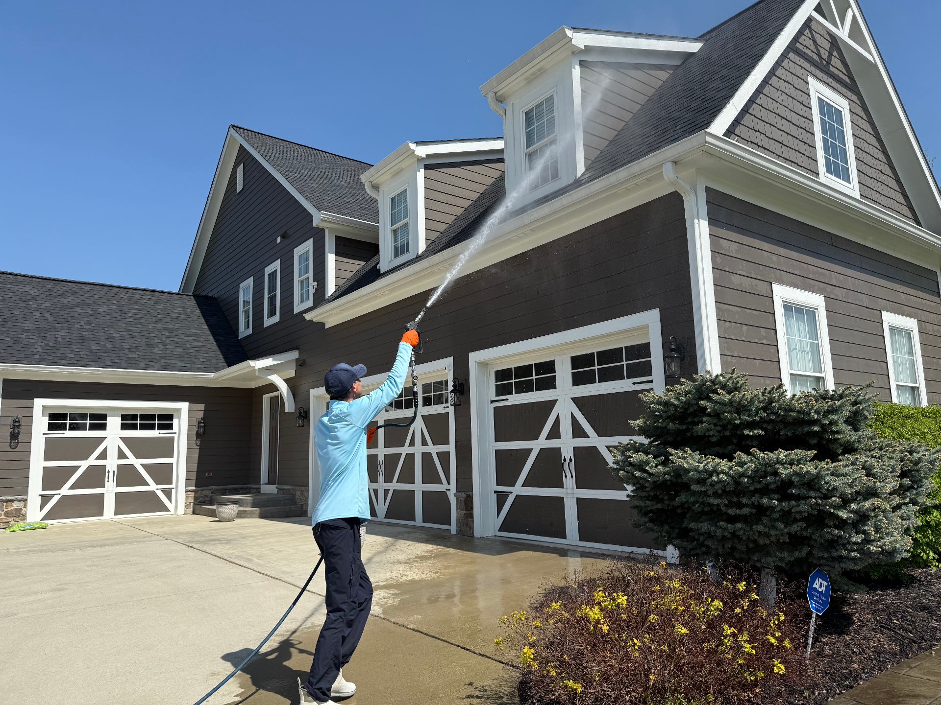 A professional pressure washing the exterior of a large home
